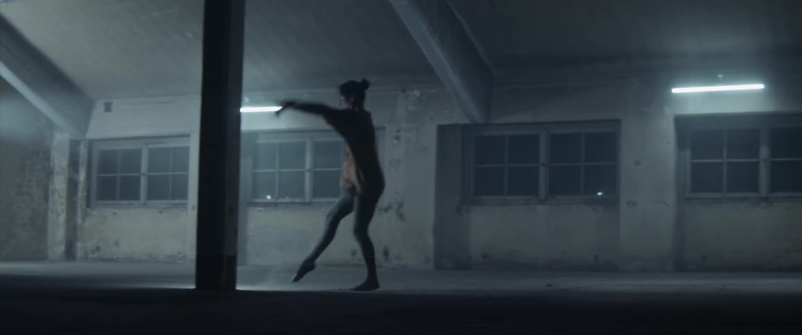 A woman dancing in a warehouse