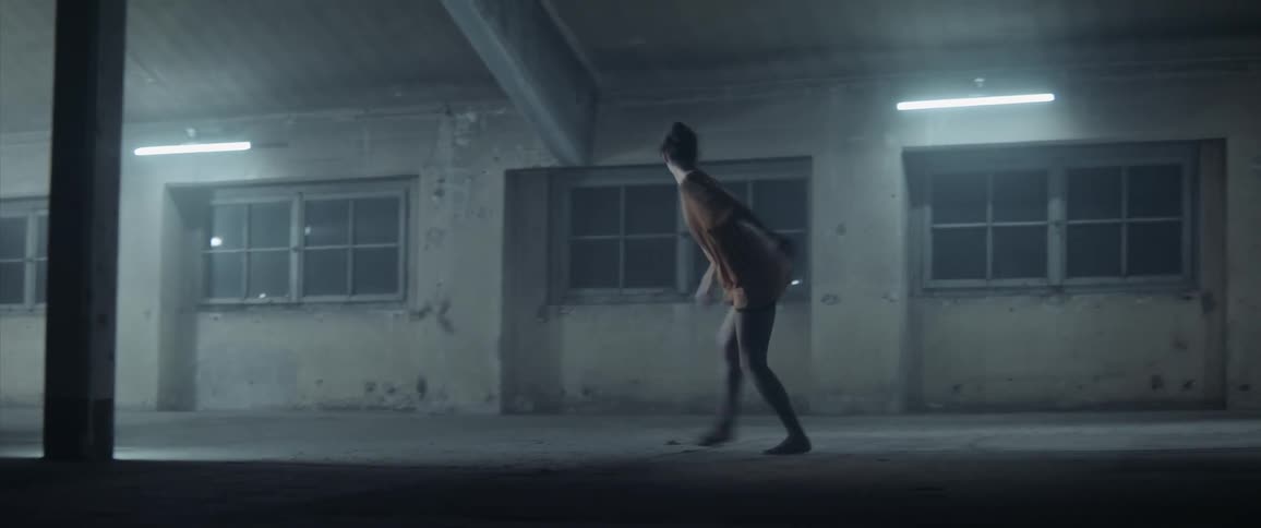 A woman contemporary dancing in an old warehouse at night