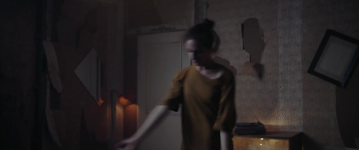 White woman dancing alone inside a house at night