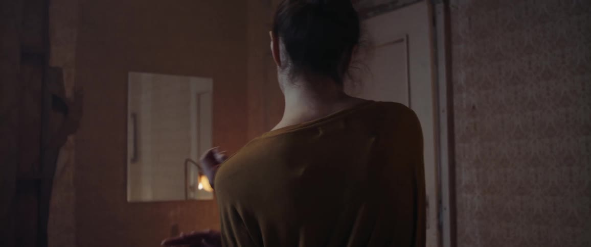A woman in a room dancing with a mirror and a lamp in the background