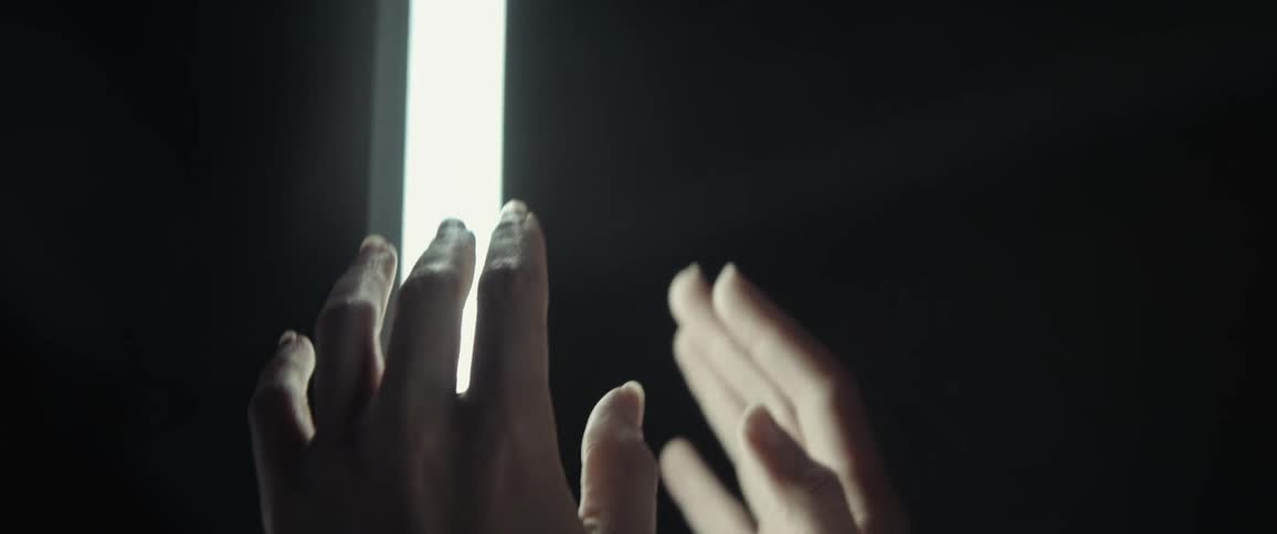 A close up of a woman reaching to a light before focusing on her face