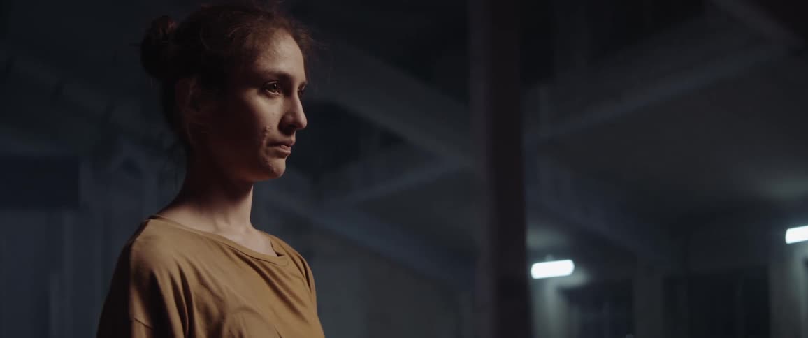 Woman standing up in a room with lights on looking up and down