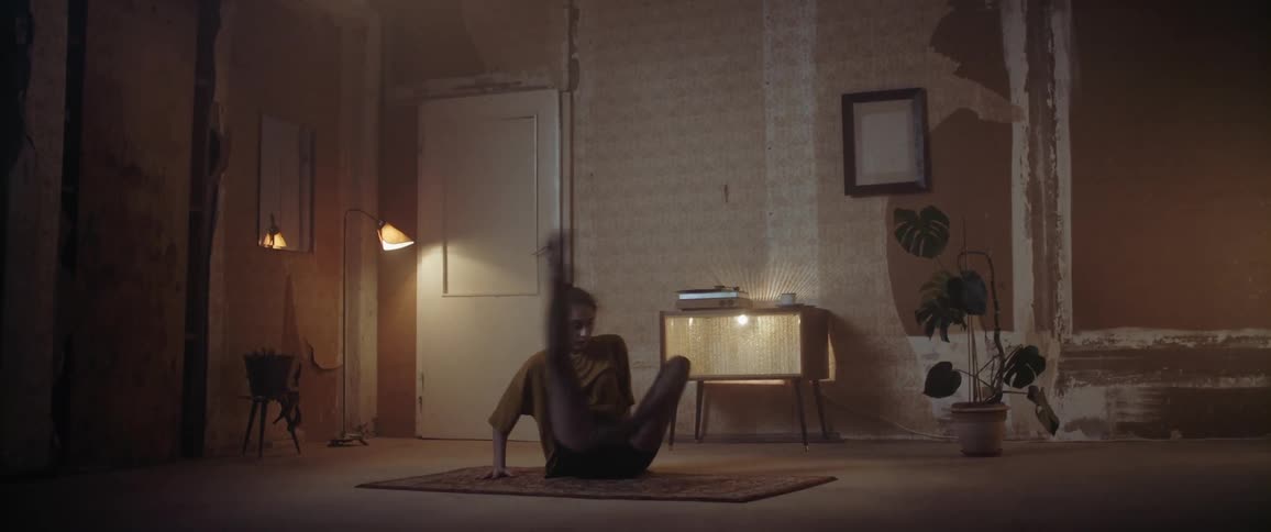 Woman performing dance moves in an apartment living room at night