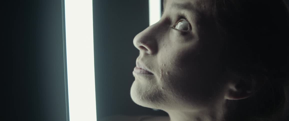 Close up of a woman looking at floating fluorescent lights in a dark room