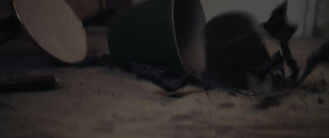 A dried out potted plant falling on the floor off a stool with a wall in the background