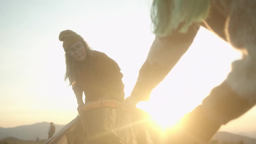 Sunlight flare shining on two women working together to put a tent together