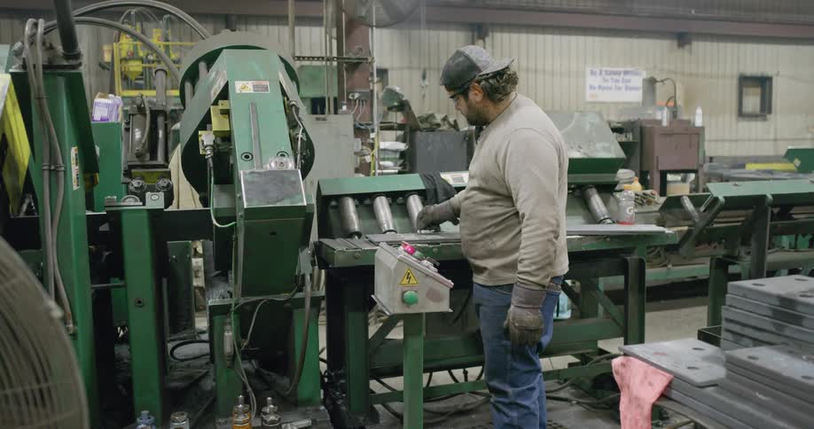 White man working on a machine inside a steel factory
