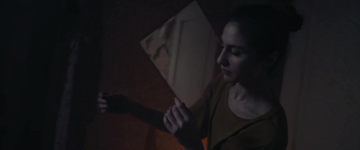 White woman dancing alone inside her room next to the door with a blinking light behind her
