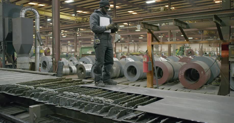 A worker marks a piece of flattened metal during the manufacturing process at a warehouse