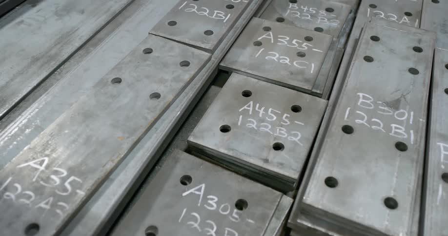Metal slabs with writing on them stacked on top of each other in a warehouse