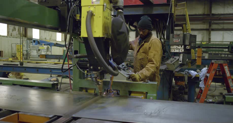 Man controls machinery working with metal sheets in factory