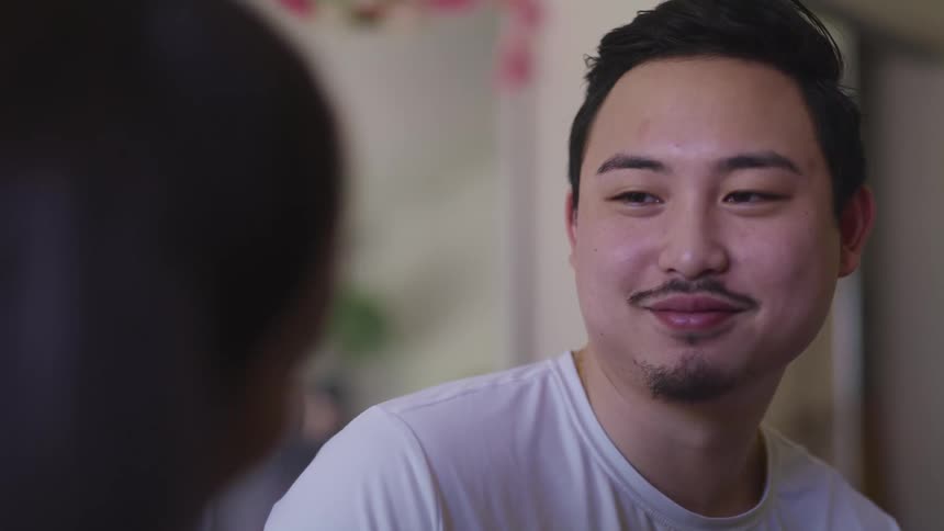 Asian man with white t shirt lovingly looks into womans eyes