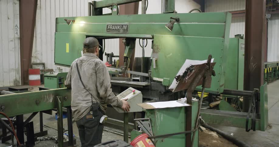Man operating a large green machine inside of a warehouse