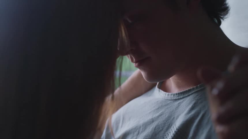Couple dancing inside the house next to a window