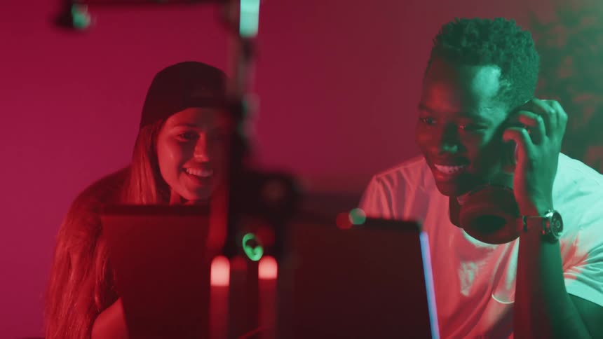 Man and woman looking to the laptop screen in a recording studio and talking to each other