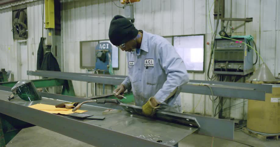 A man working in a factory marks metal