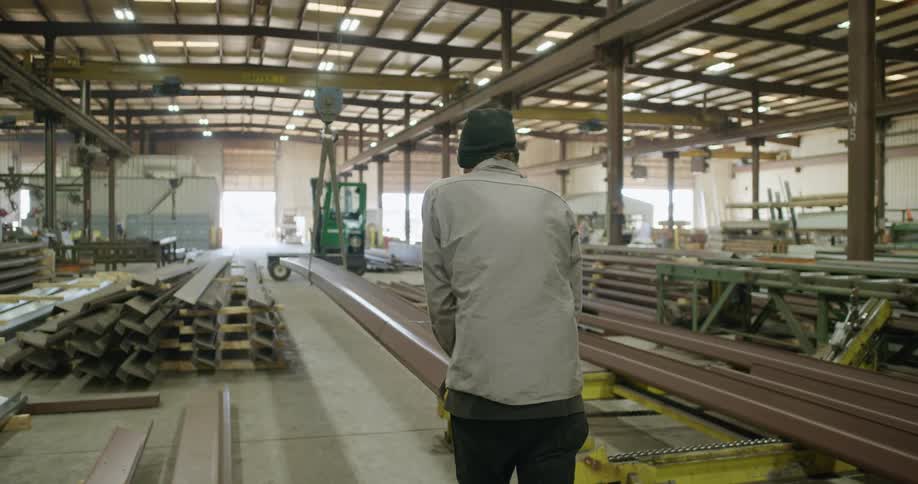 Worker pushing metal profiles on a crane in a factory on a warehouse