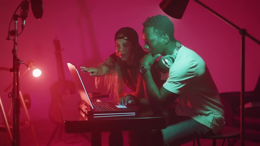 A man and woman are sitting by a computer and talking