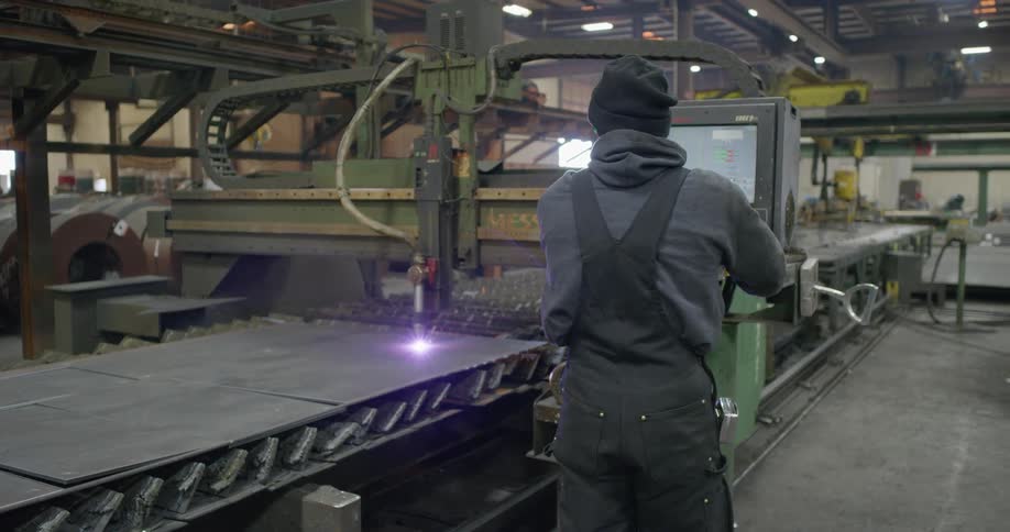 A man in a factory works with a large tool