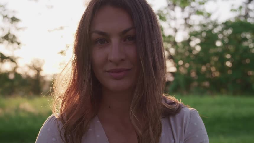 A woman in a polka dot blouse poses in a field