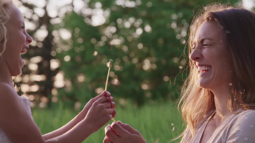 Mother and daughter playing and laughing together at the park with flowers