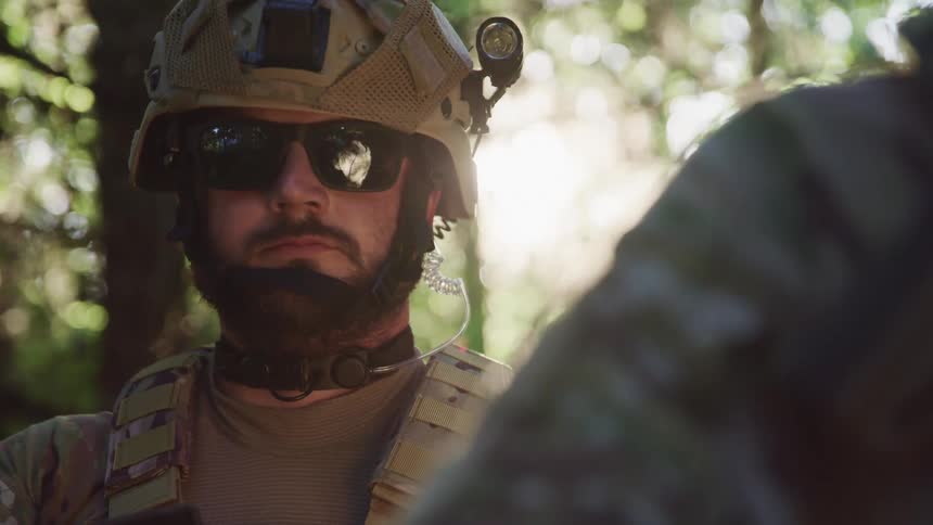 Us army soldier standing in a forest loking at the camera