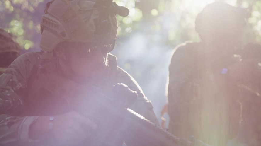 Group of soldiers pointing guns in the fog on a forest at sunset