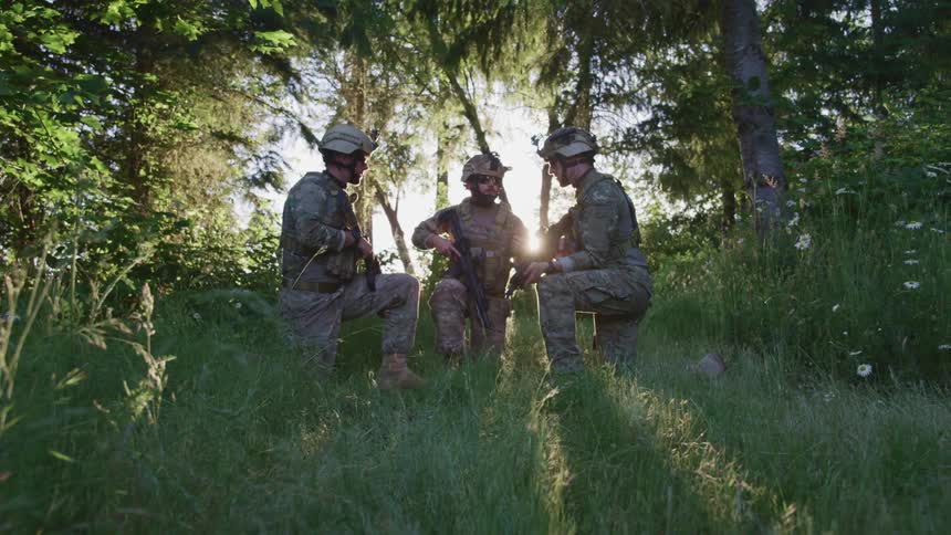 Soldiers crouched together in the middle of the forest