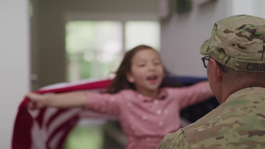 American soldier being greeted by his daughter at home wearing an american flagg