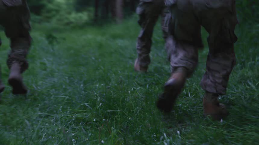 Three soldiers in military gear running in a forest at daytime