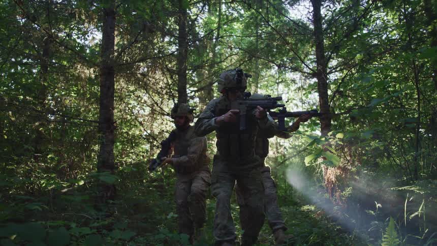 Three soldiers holding guns and walking through a forest at daytime