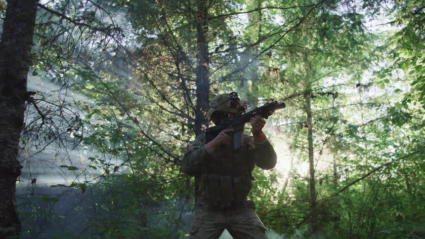 A soldier is aiming his rifle in the forest