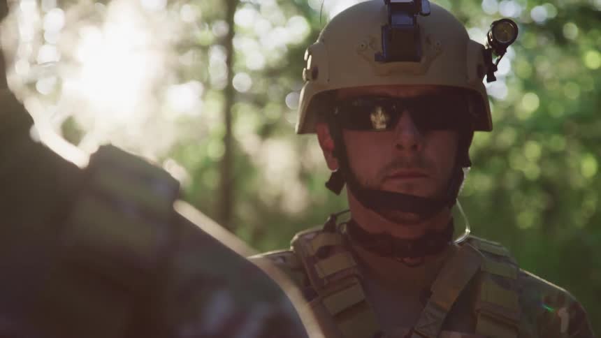 Soldiers with helmets standing in a forest with trees and the sky in the background