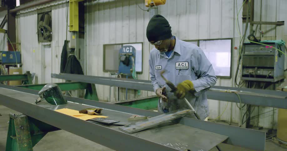 Man marks metal piece in factory constructing steel unit