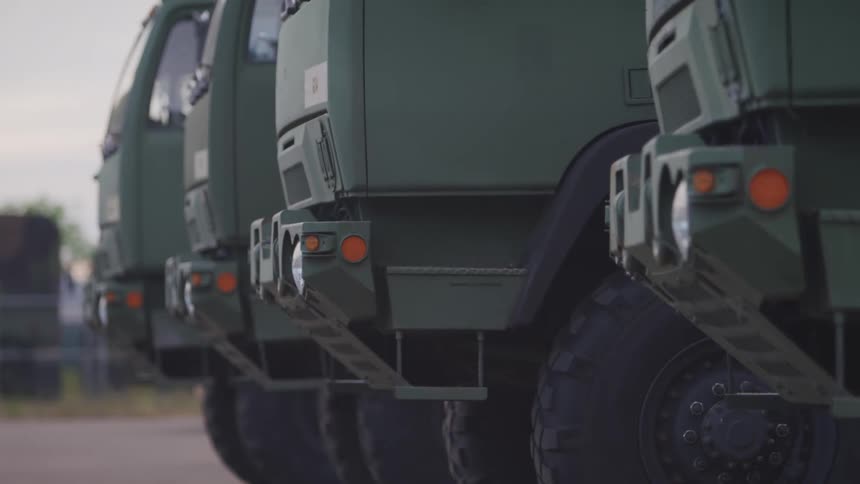 Bumper of green trucks parked outdoors at evening