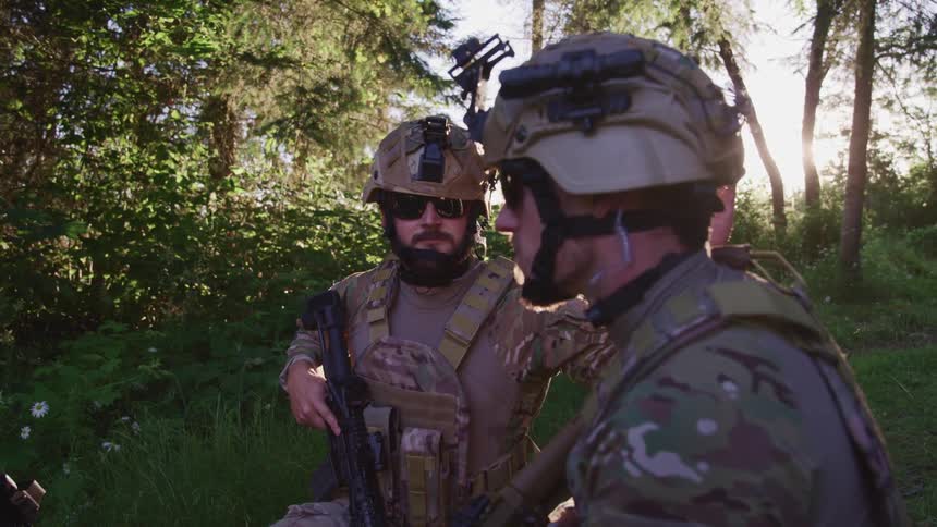 Soldiers with helmets and rifles in the forest with plants and trees in the background