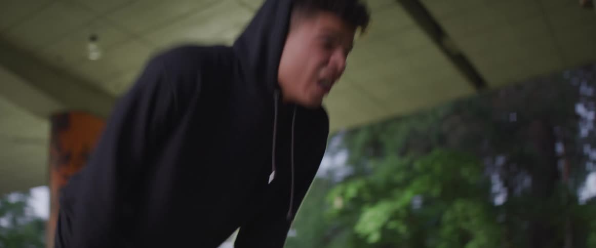 A teenage boy pants catching his breath and then takes off running on a basketball court in a park
