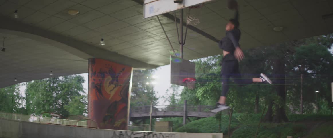 Teenager boy playing basketball alone in an empty basketball court