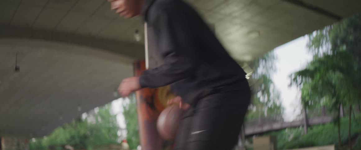 Black teenager boy practicing basketball alone in a basketball court