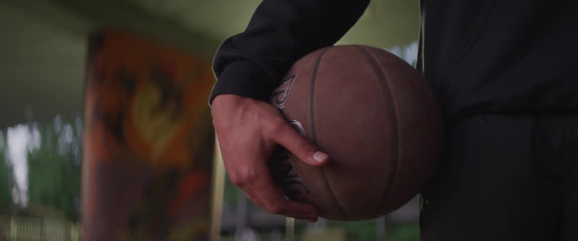 Black boy holding a basketball next to his body with his hand