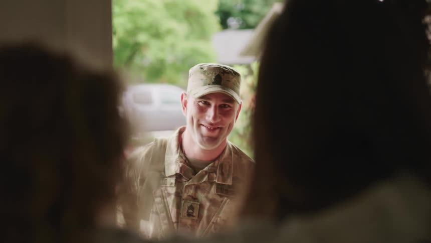 Military man happily opening the door of his house and seeing his wife