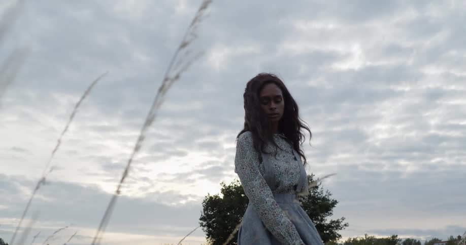 A young woman standing in a field turns around