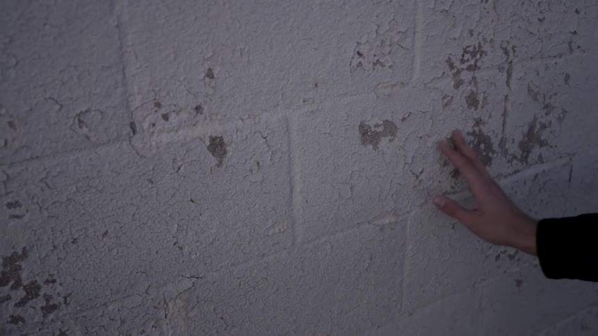A person touches a painted wall while walking