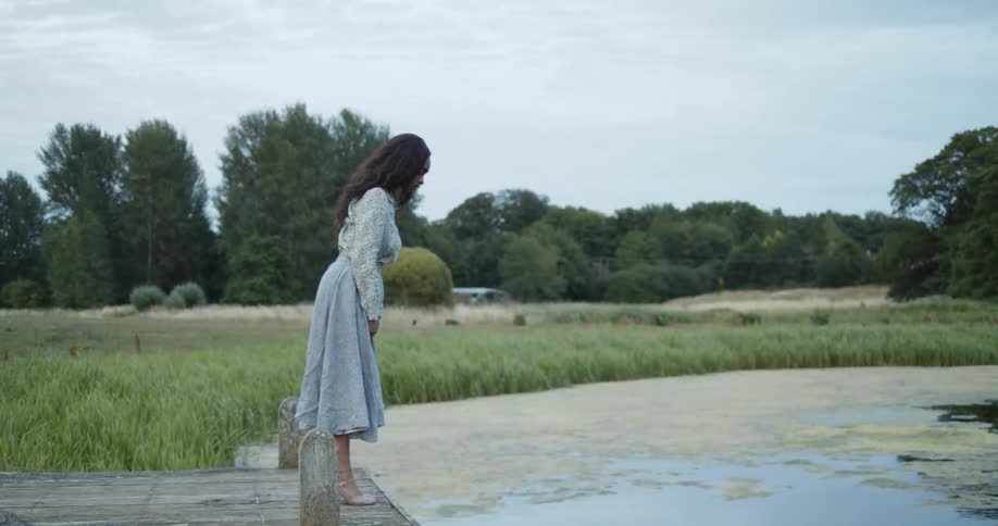 A woman leans on the pier looking into the marsh