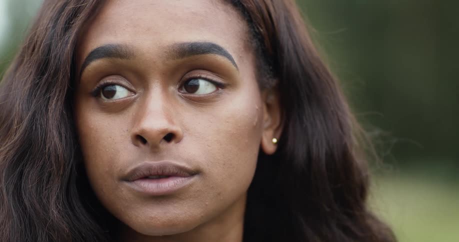 Black woman wearing a studded earring raises her head then blinks her eyes and turns her head