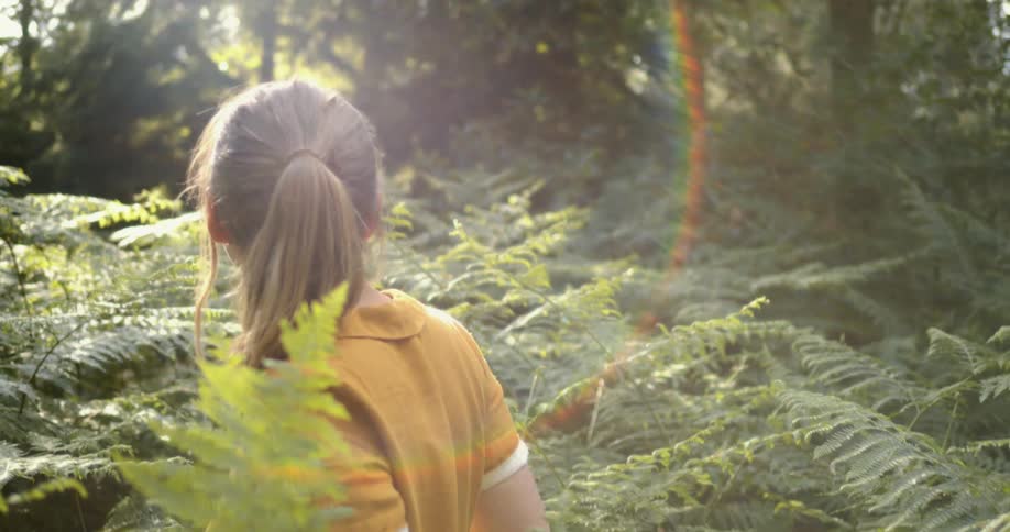 A woman looks behind her in the woods and blows a kiss