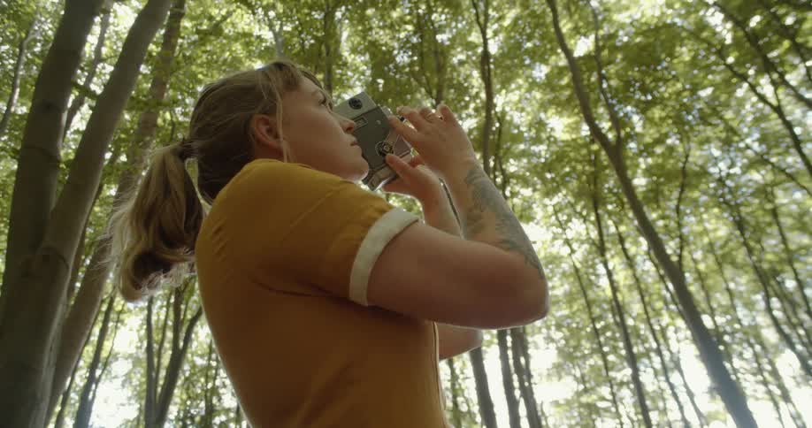 A woman taking a video in a forest