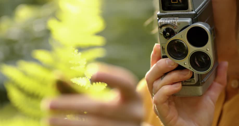 White woman taking a picture of a plant and holding a camera