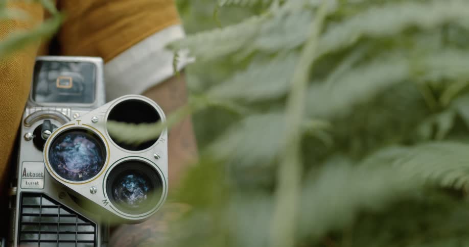 Young woman holding a vintage film camera in the forest