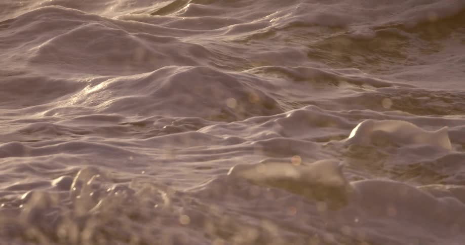 Foam over the crashing ocean waves at sunset